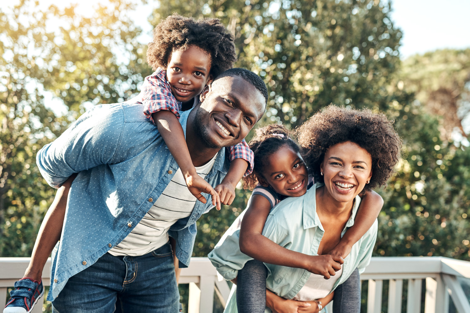 A mom and dad give piggy back rides to their two children outside in Lakeland, FL before visiting their family dentist together