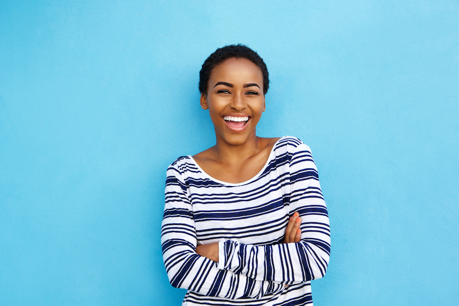 Black woman in a striped shirt smiles after professional teeth whitening