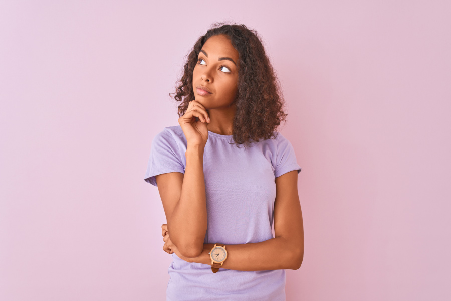 Brunette Black woman in a lavender shirt wonders what dental restoration is right for her smile