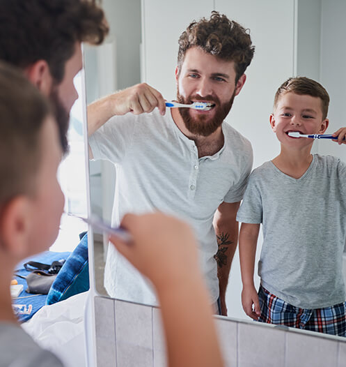 father and son brushing their teeth together