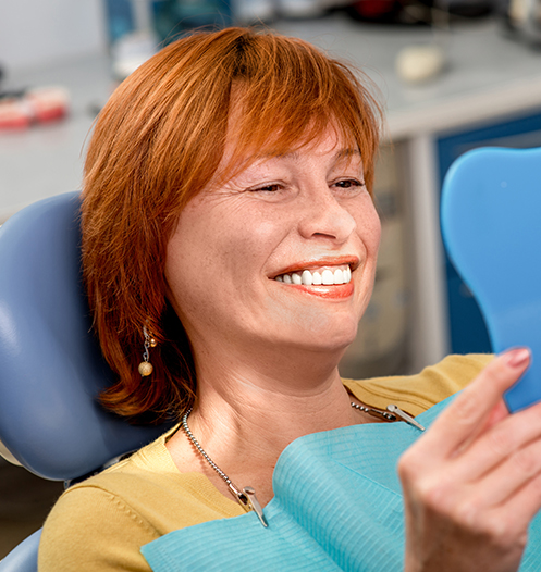 woman smiling into mirror at dentist